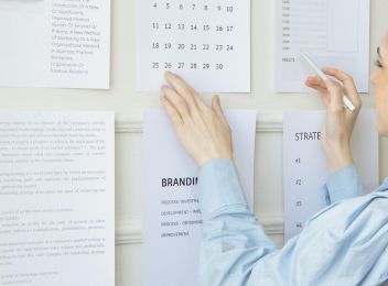 Femme observant un mur rempli de documents visuels et concepts créatifs, illustrant le processus de création d’une identité de marque.